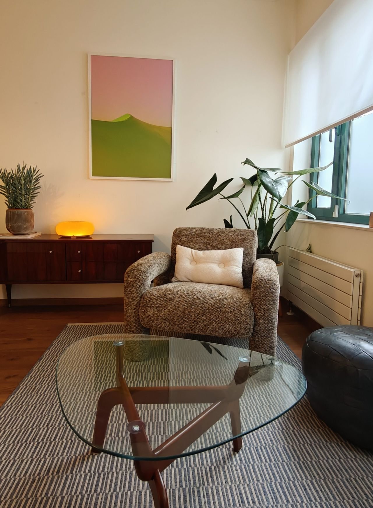 Een zetel met een kussen in de spreekkamer, naast een kast met een lamp en een plant.